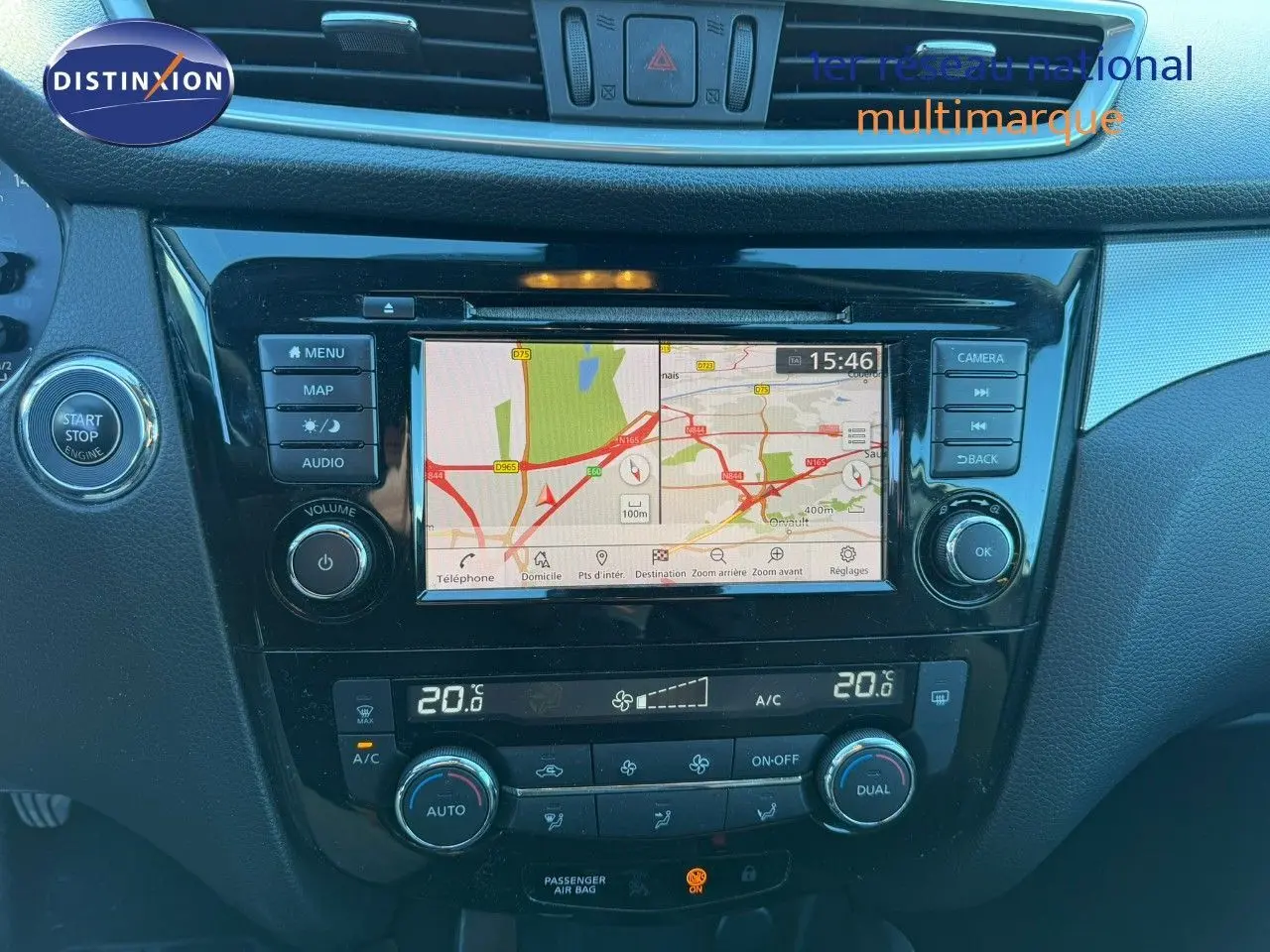Vue rapprochée du tableau de bord du Nissan Qashqai blanc nacré, avec écran tactile de navigation et commandes climatisation.