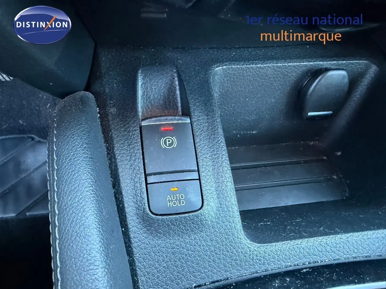 Gros plan sur la console centrale noire du Nissan Qashqai blanc nacré, montrant le frein à main électronique et le bouton Auto Hold.