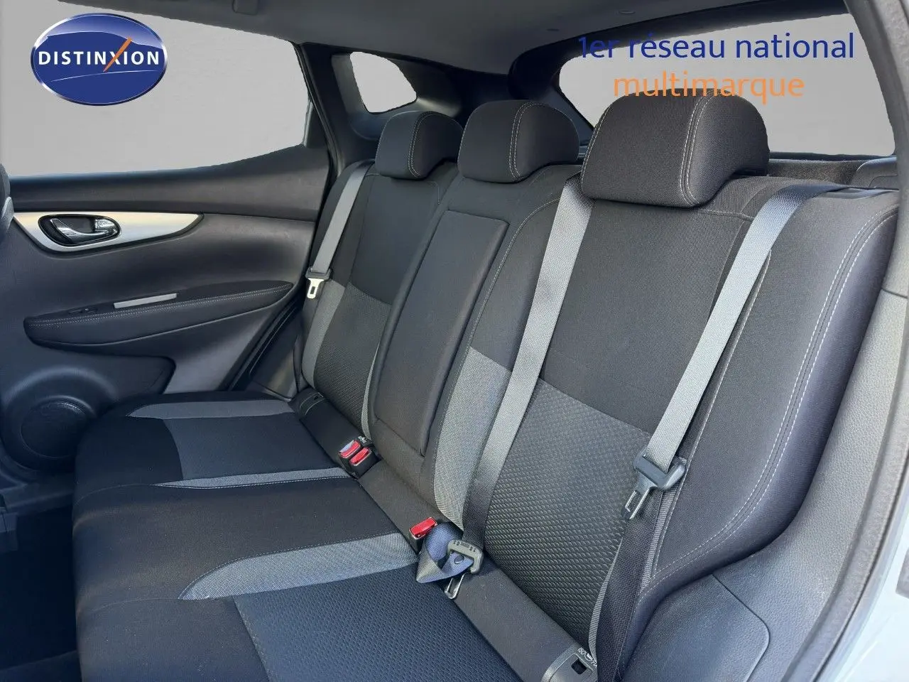 Vue intérieure du siège arrière côté gauche d'un Nissan Qashqai blanc nacré, avec ceintures de sécurité et appuie-têtes visibles.