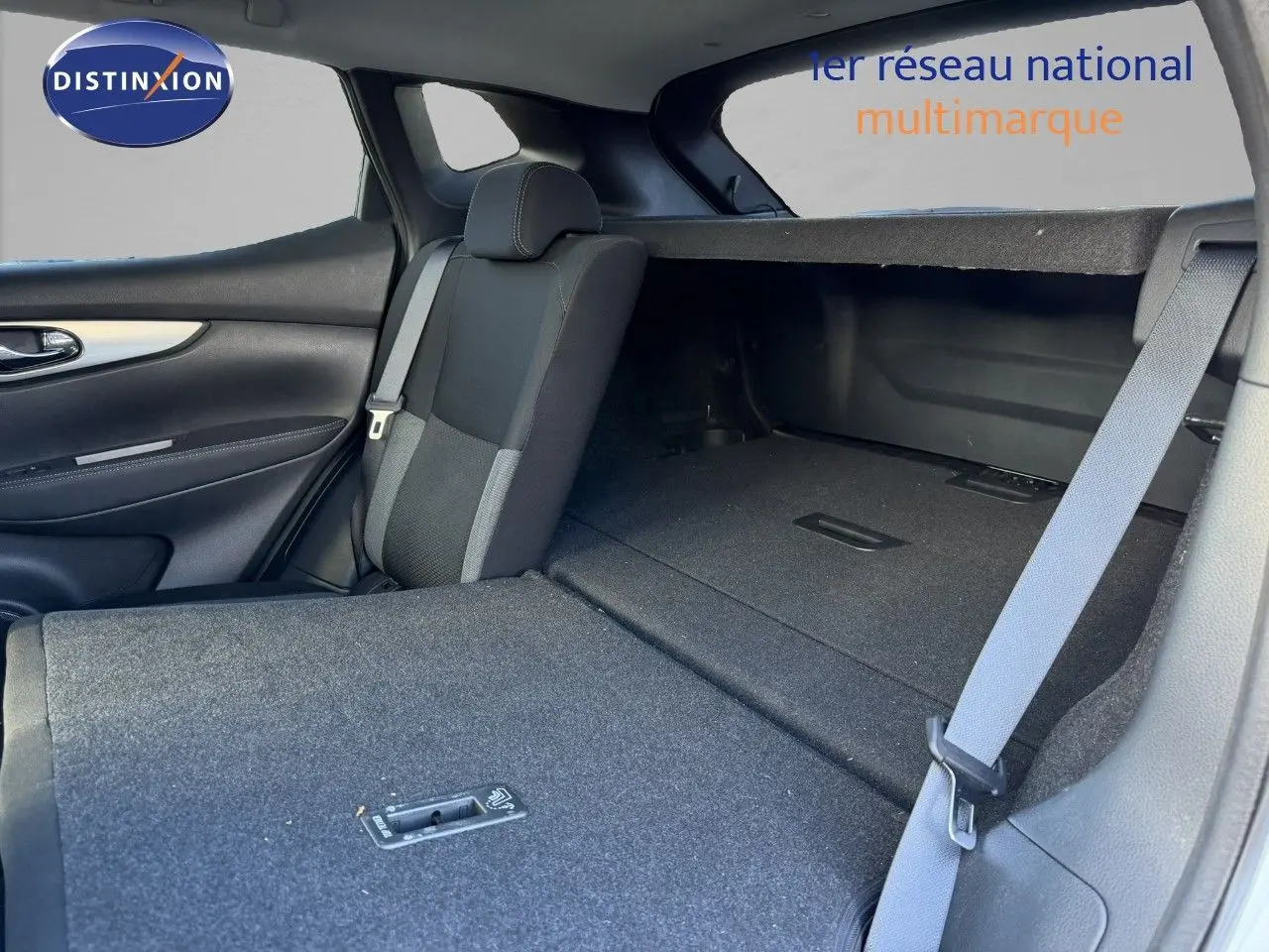 Vue intérieure arrière du Nissan Qashqai blanc nacré, siège rabattable et espace de coffre visible.