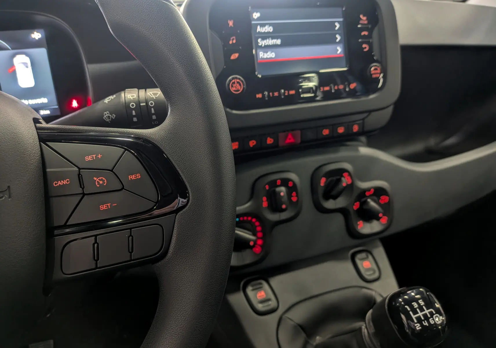 Intérieur de la Fiat Panda 1.0 Hybrid 2025, vue rapprochée sur le volant et la console centrale avec boîte manuelle noire.