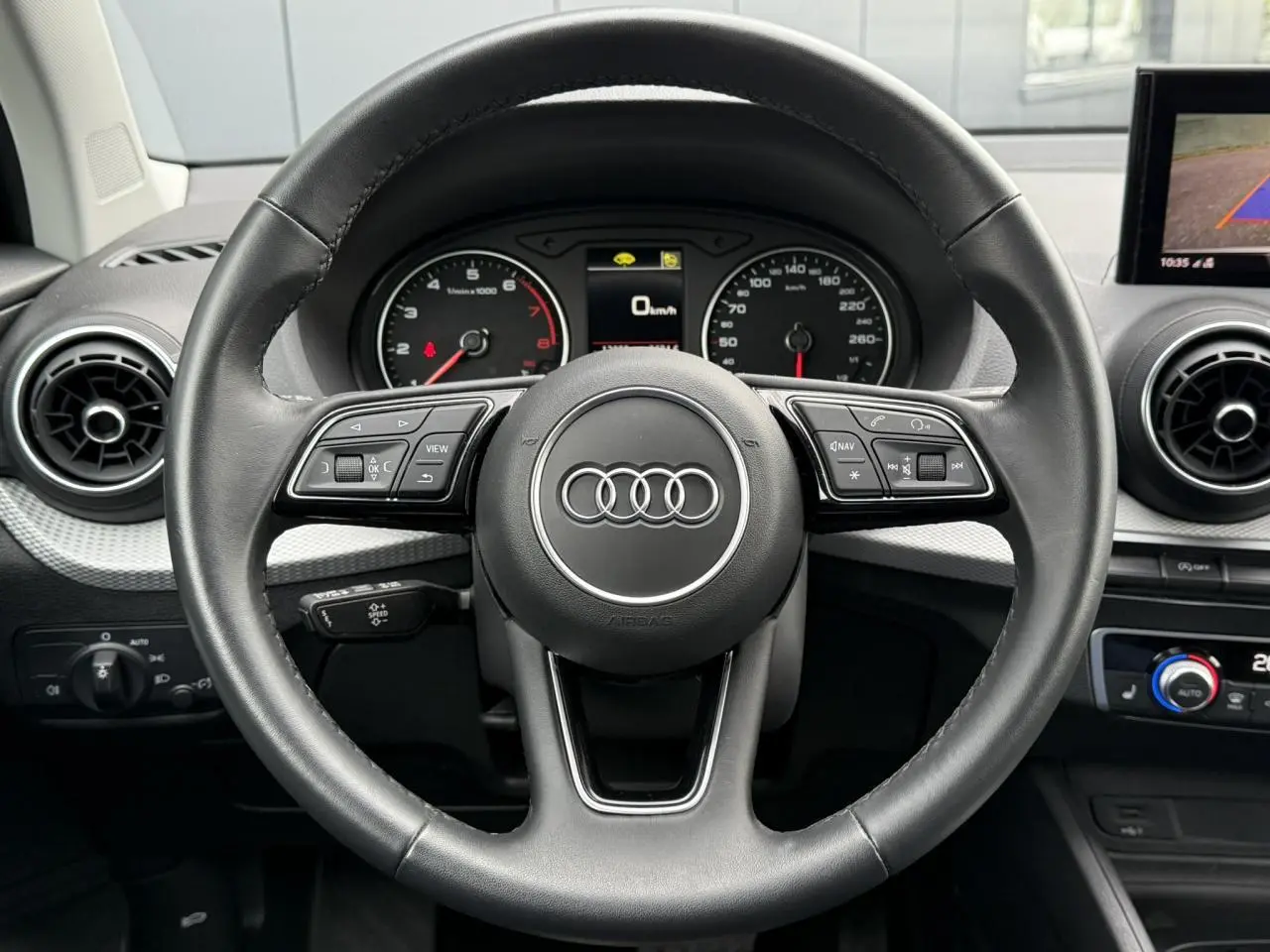 Vue centrée sur le volant noir de l'Audi Q2 35 TFSI S-Line 2023 avec tableau de bord et commandes intégrées visibles.