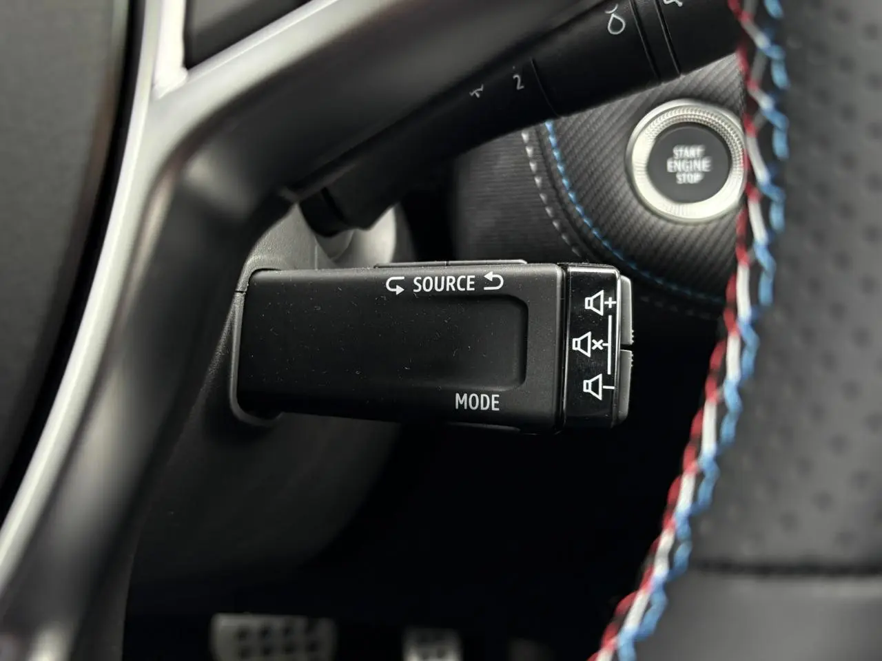 Gros plan sur la commande multimédia au volant du Renault Captur Esprit Alpine avec surpiqûres tricolores.