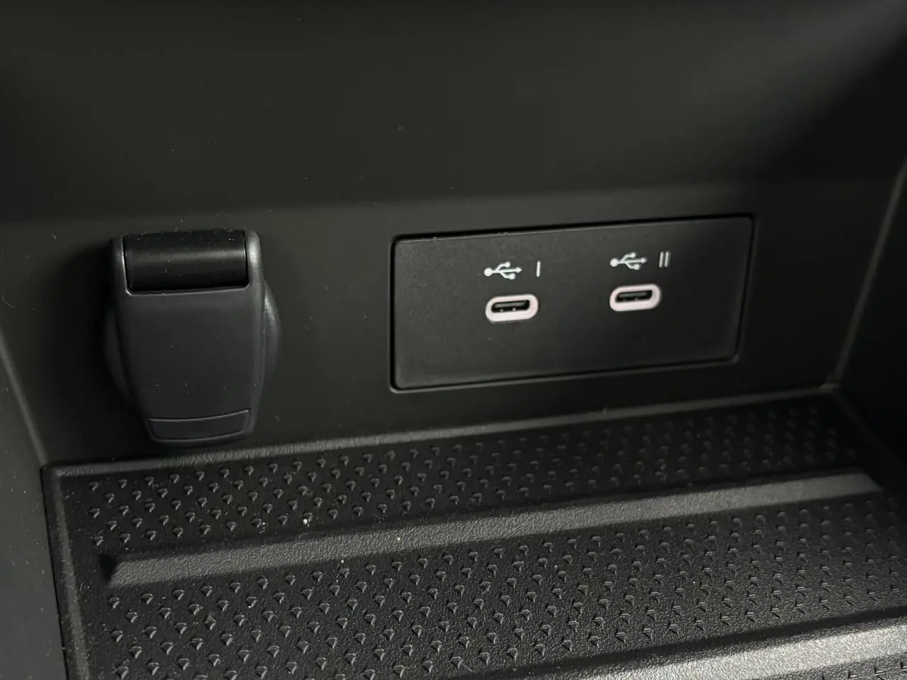 Gros plan sur deux ports USB-C et une prise 12V noirs dans le compartiment avant d'un Renault Captur gris.