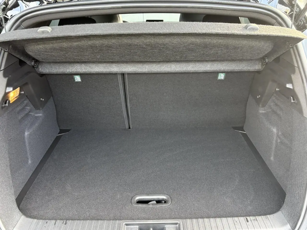 Coffre ouvert vu de l’arrière du Renault Captur gris Rafale, intérieur noir avec cache-bagages déployé.