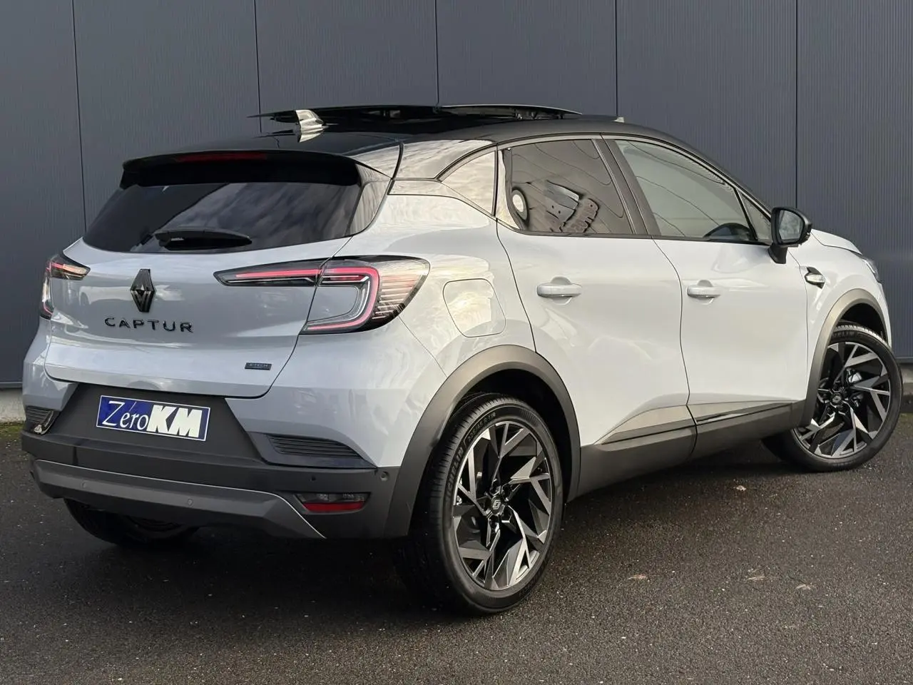 Vue 3/4 arrière droite du Renault Captur gris Rafale avec toit noir ouvrant et jantes aluminium noires.
