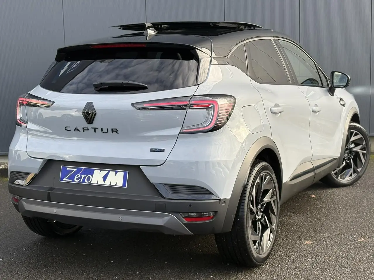 Vue 3/4 arrière droite du Renault Captur gris Rafale avec toit noir ouvrant et jantes noires distinctives.