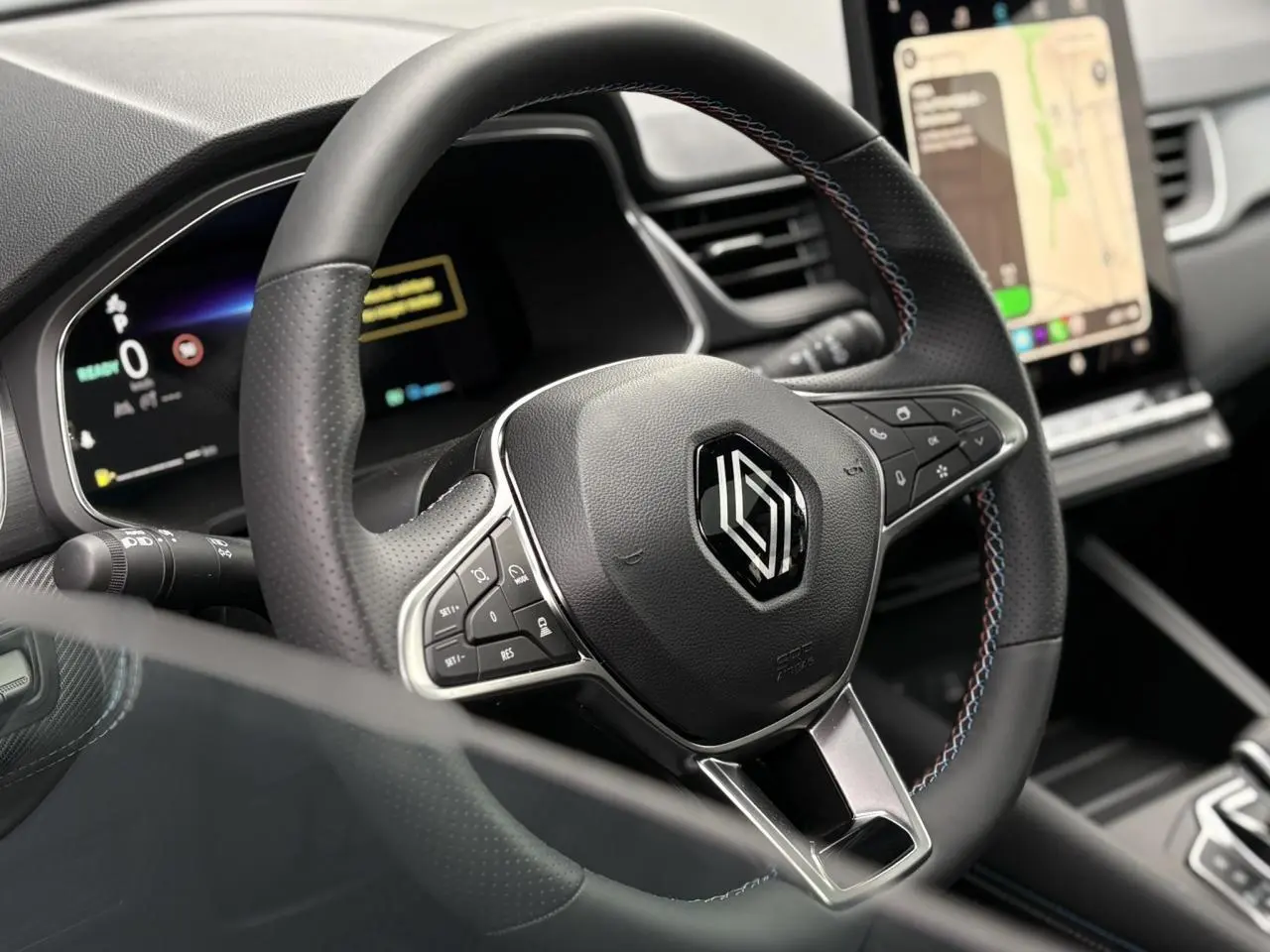 Gros plan sur le volant noir avec surpiqûres tricolores et tableau de bord numérique du Renault Captur Esprit Alpine 2025.