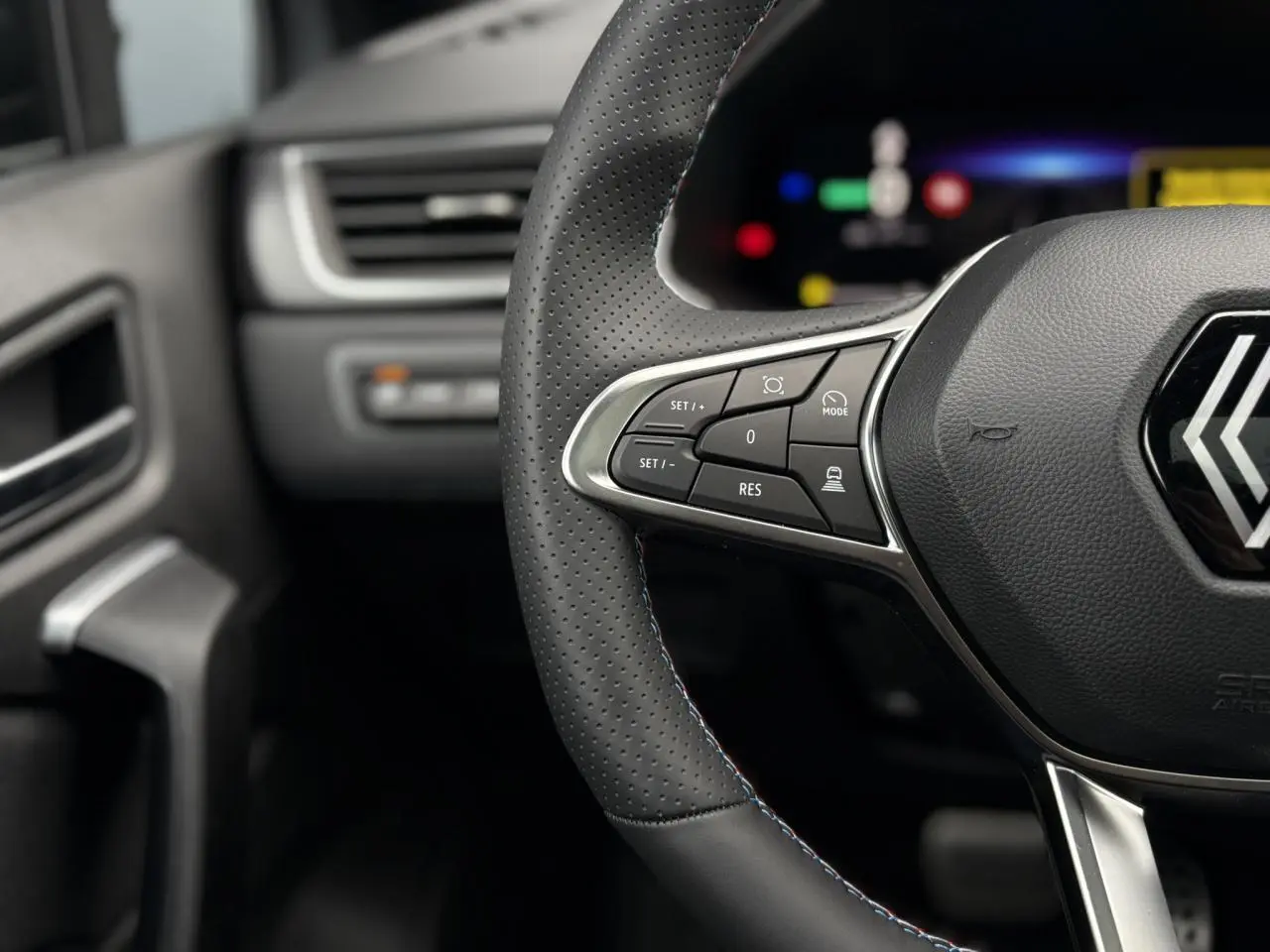 Gros plan sur le volant perforé avec surpiqûres tricolores et commandes multifonctions du Renault Captur Esprit Alpine 2025.