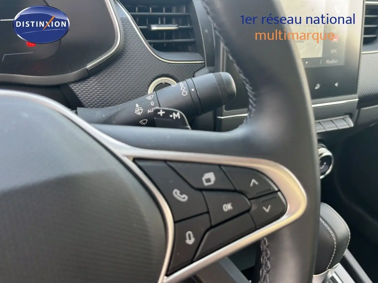 Gros plan sur le volant et commandes multifonctions du Renault Arkana gris Cassiopée, intérieur moderne avec tableau de bord visible.