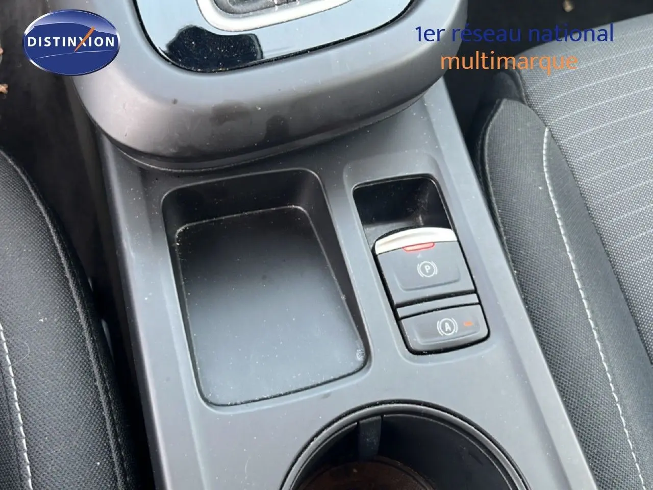 Gros plan sur la console centrale noire du Renault Arkana 2025, montrant les boutons de frein à main et auto hold.