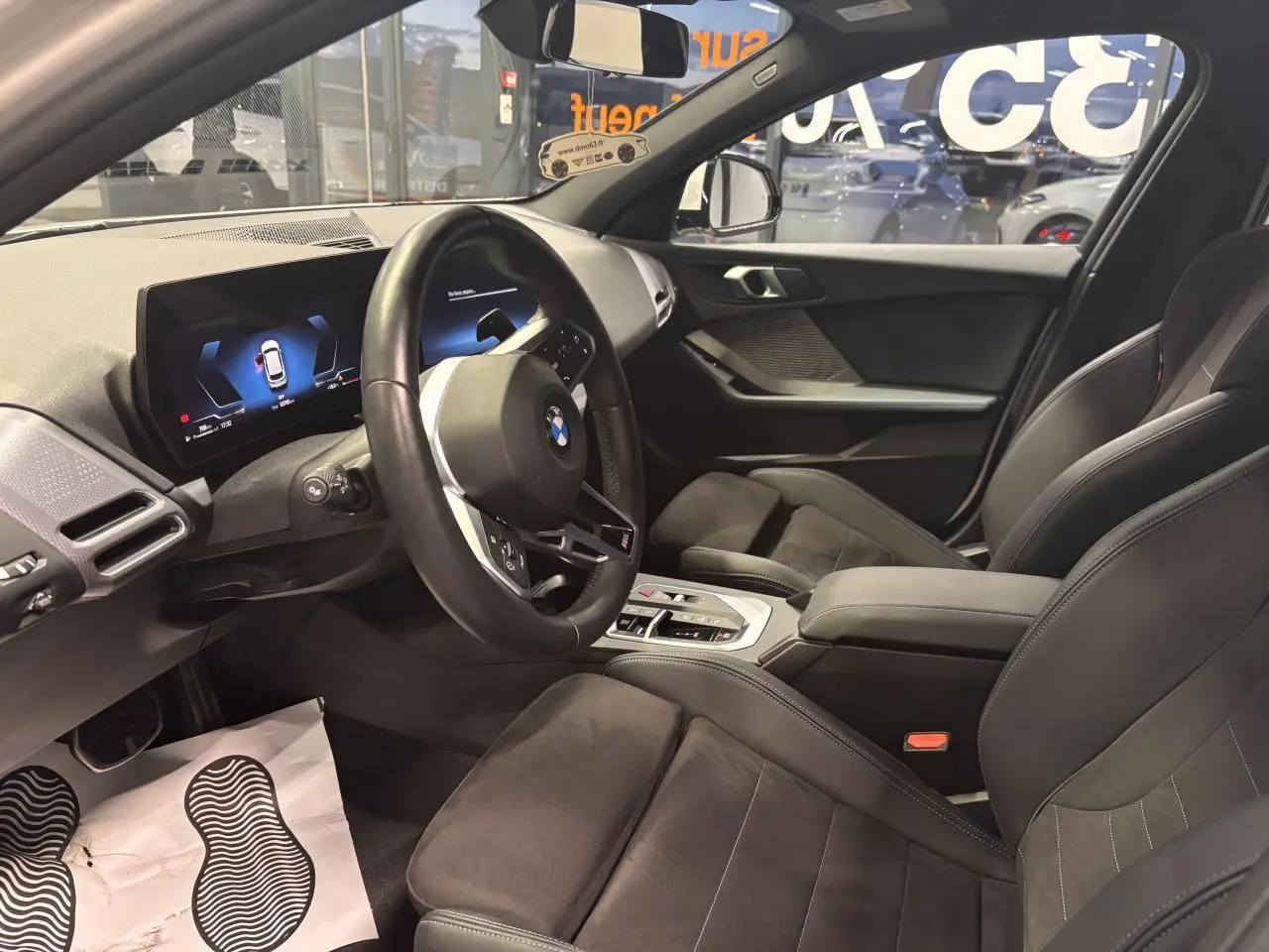 Intérieur avant droit de BMW Série 1 118d M Sport noir, sièges sport Alcantara et tableau de bord numérique.