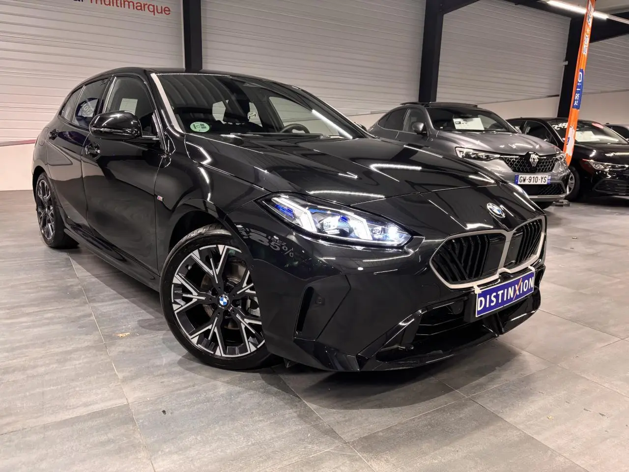 BMW Série 1 118d M Sport noir métal vue 3/4 avant avec calandre M Sport et jantes alliage 18 pouces bicolores.