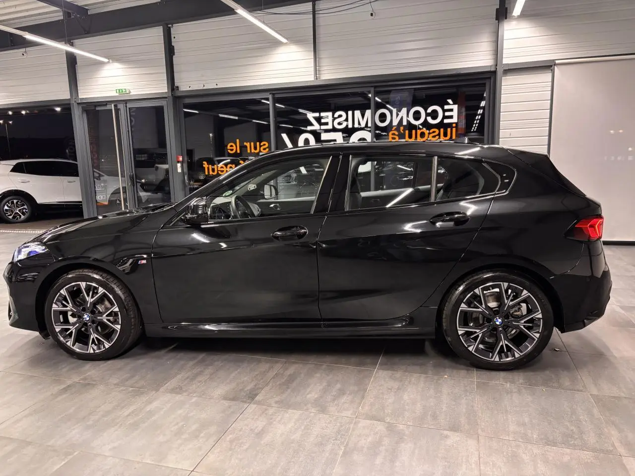 BMW Série 1 118d M Sport noir métal vue de profil côté gauche avec jantes alliage 18 pouces et détails M Sport visibles.