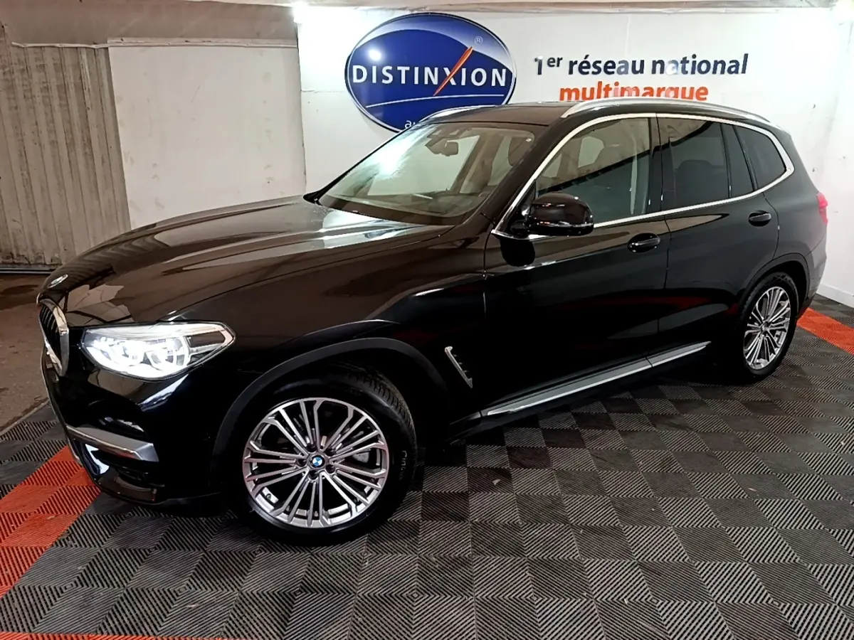 BMW X3 sDrive18d noir en 3/4 avant droit avec phares allumés et jantes alliage multibranches.
