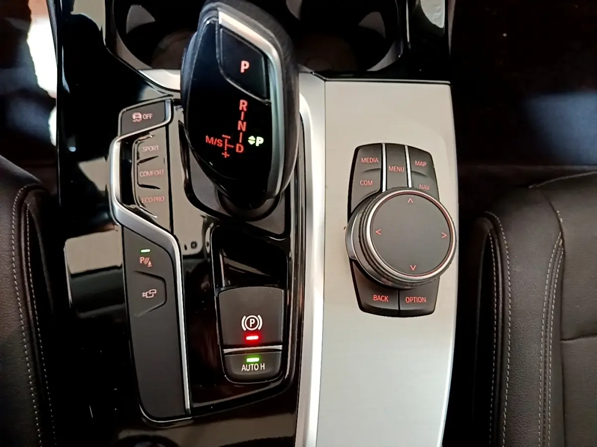 Vue rapprochée de la console centrale noire et argentée du BMW X3 sDrive18d 2019 avec levier de vitesse automatique et molette de contrôle.