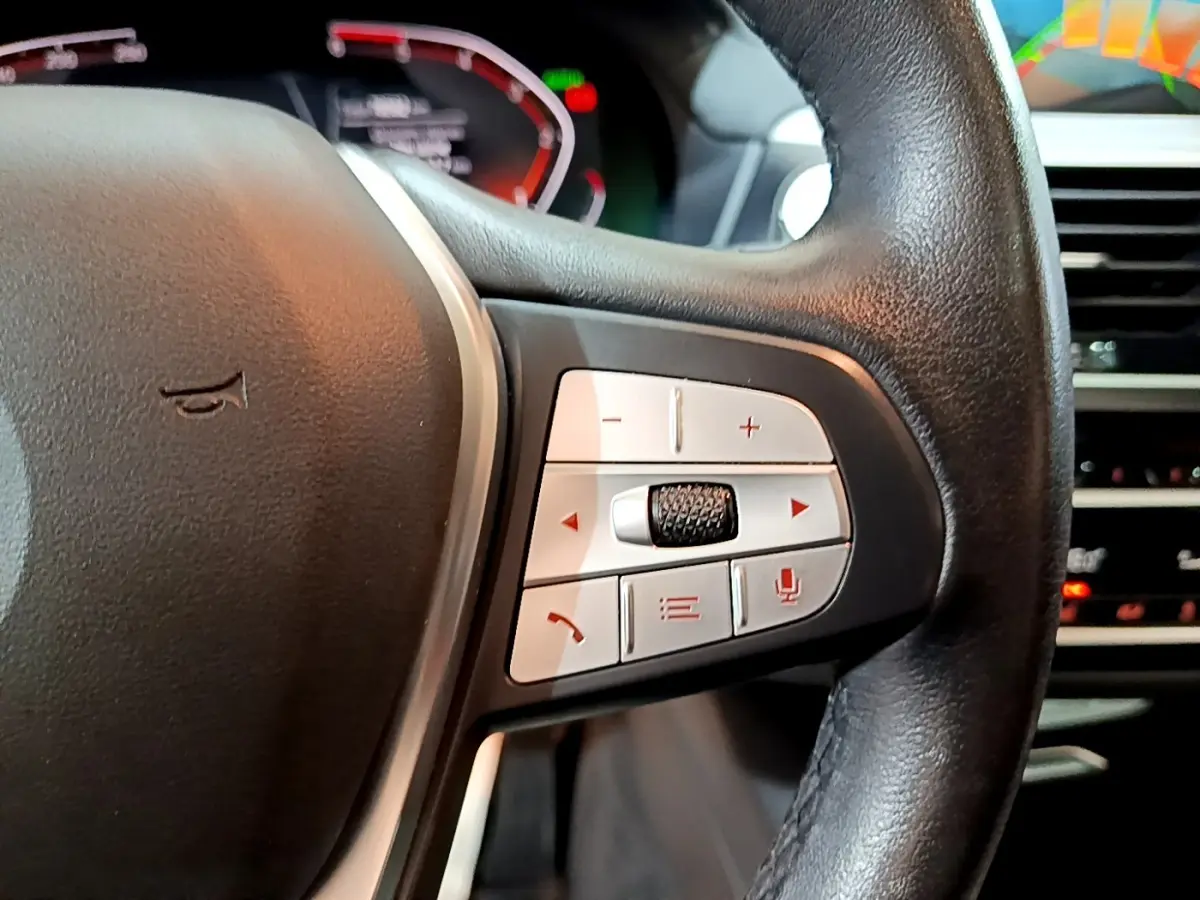 Gros plan sur les commandes multifonctions côté droit du volant cuir noir du BMW X3 sDrive18d 2019, tableau de bord en arrière-plan.