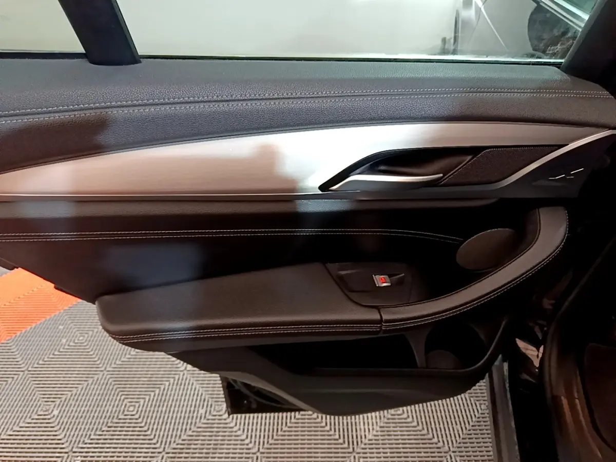 Vue intérieure du panneau de porte côté gauche noir avec insert aluminium brossé et commande de lève-vitre BMW X3 2019.