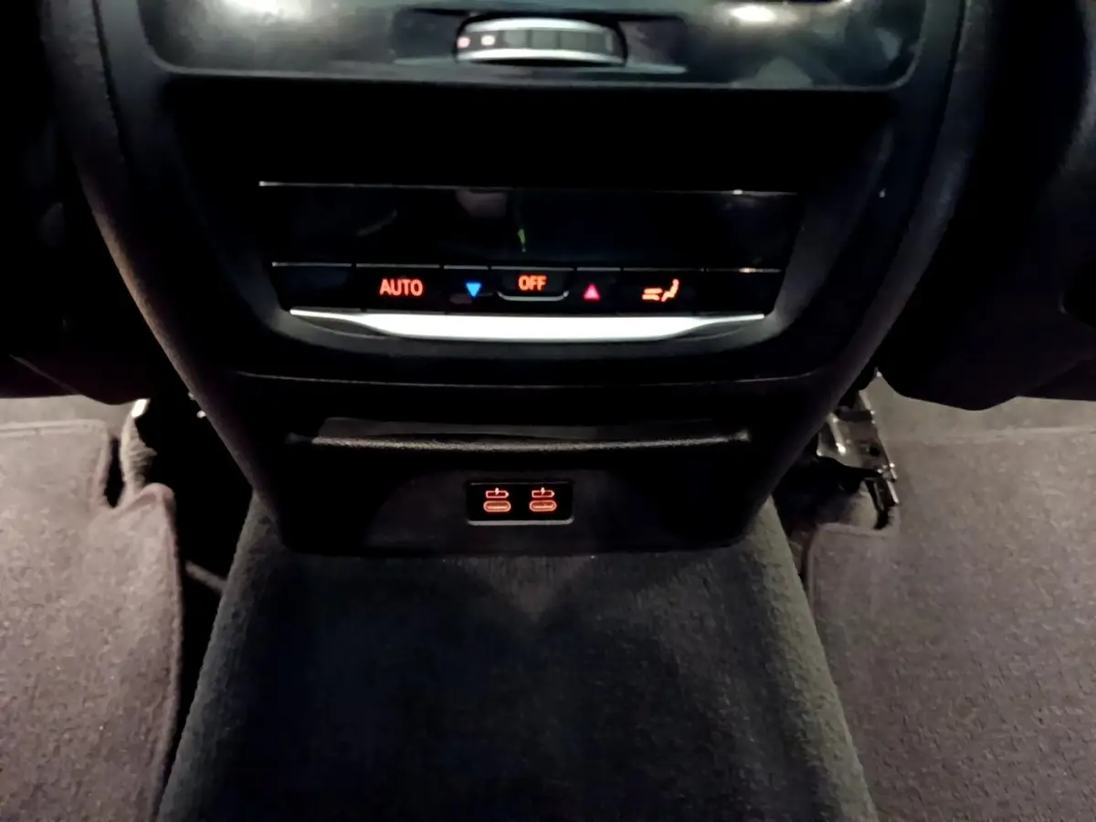 Détail de la console centrale arrière noire du BMW X3 sDrive18d 2019 avec commandes climatisation et ports USB éclairés.