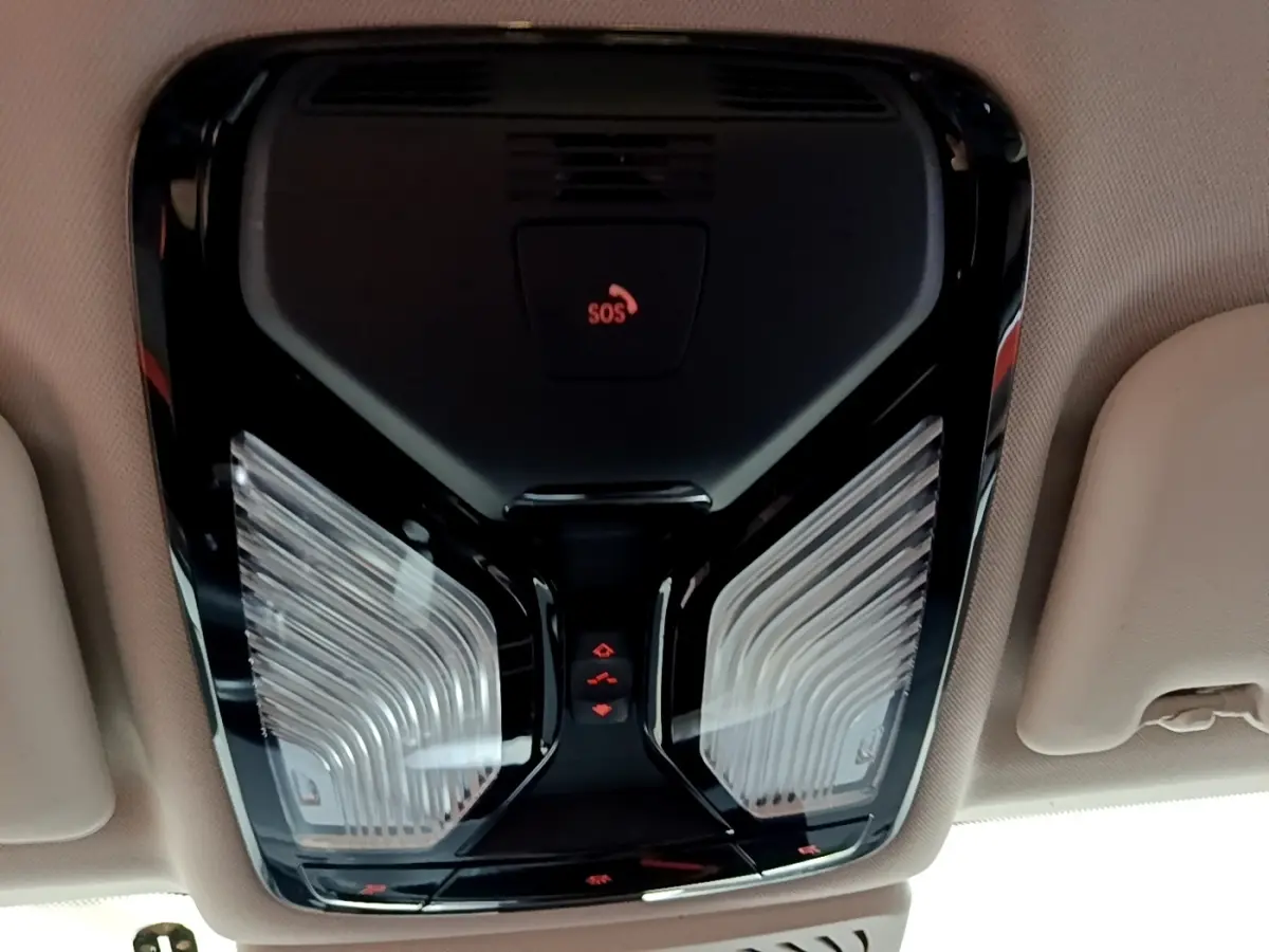 Plafonnier intérieur noir avec boutons de commande et témoin SOS, vue en contre-plongée dans un BMW X3 noir.