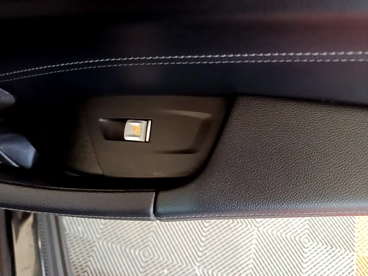 Gros plan sur le bouton de condamnation centralisée sur la porte intérieure noire d’un BMW X3 sDrive18d 2019.