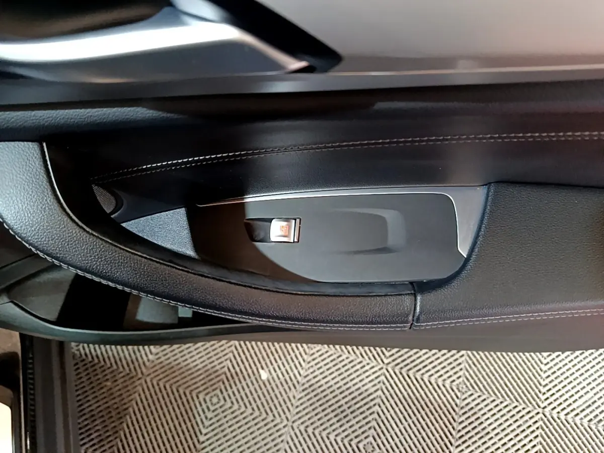 Détail de la poignée intérieure noire côté porte avant d’une BMW X3 sDrive18d 2019 avec bouton de verrouillage.
