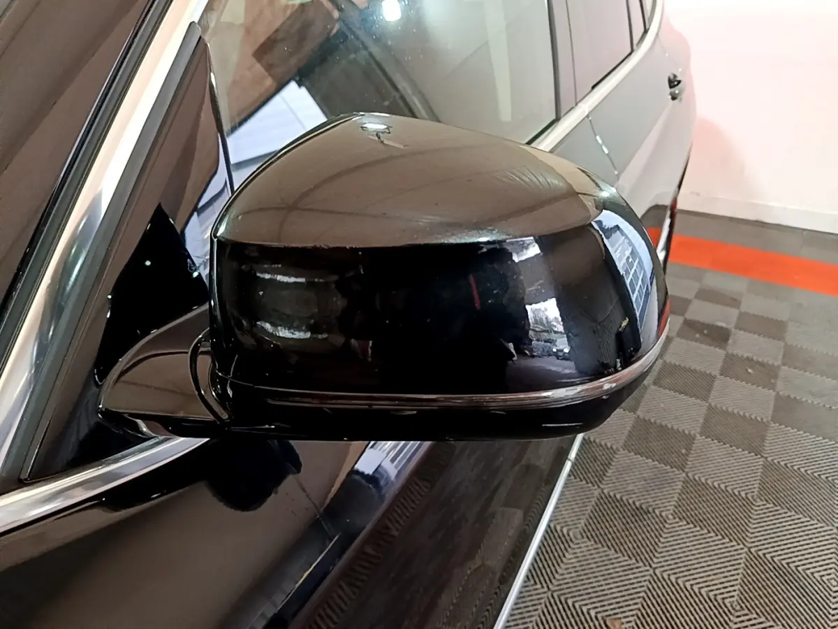 Rétroviseur côté gauche noir brillant d’un BMW X3 sDrive18d Luxury 2019, avec carrosserie noire visible en arrière-plan.