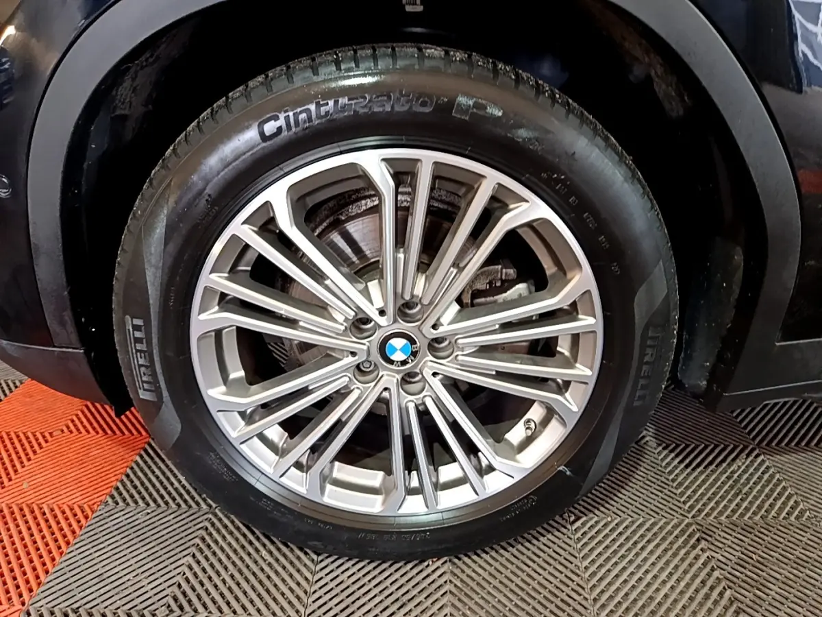 Gros plan sur la roue avant droite d’un BMW X3 noir, jante alliage multi-branches et pneu Pirelli.