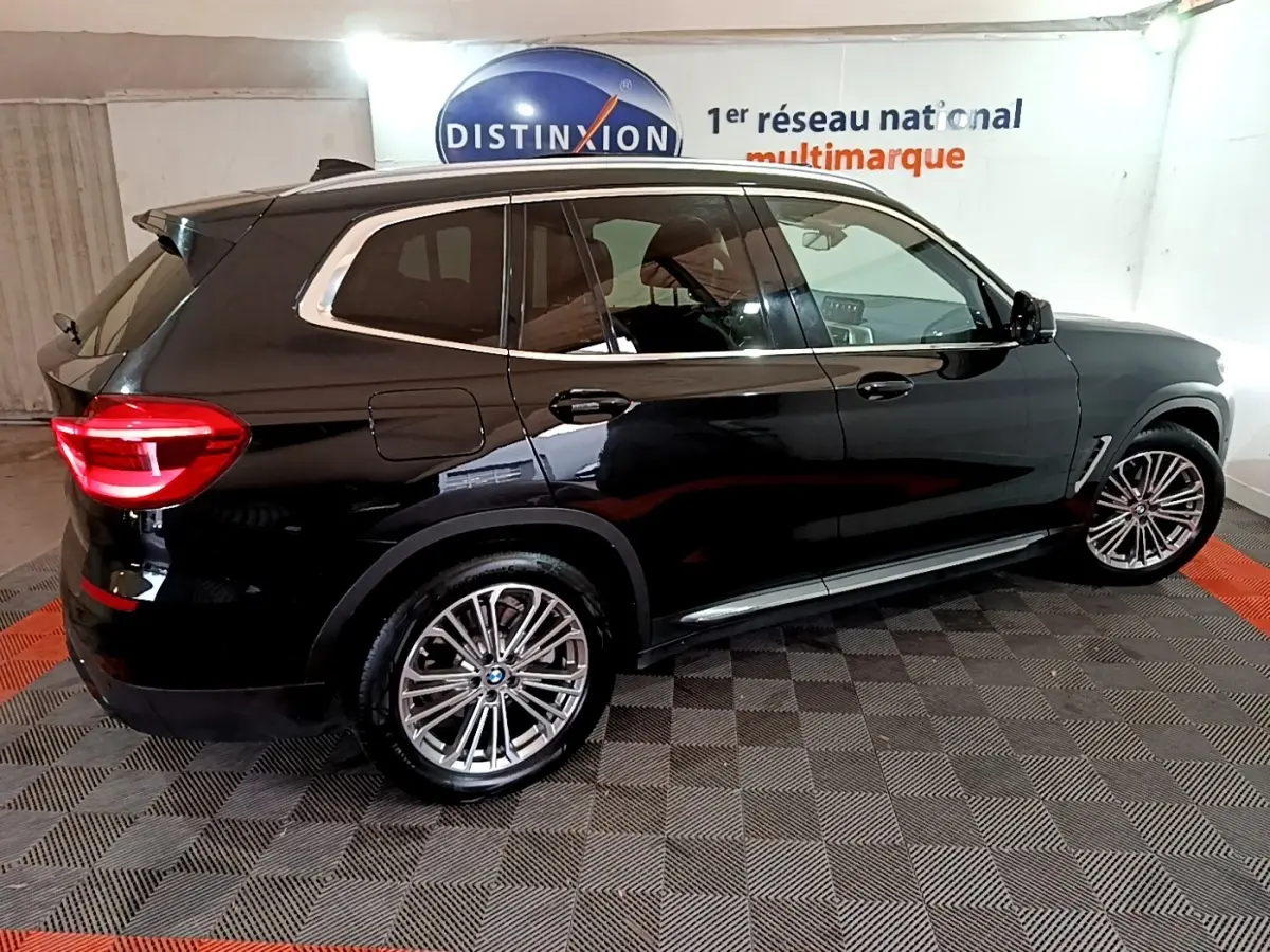 BMW X3 sDrive18d noir vue de profil droit en intérieur, soulignant ses jantes alliage et vitres teintées.