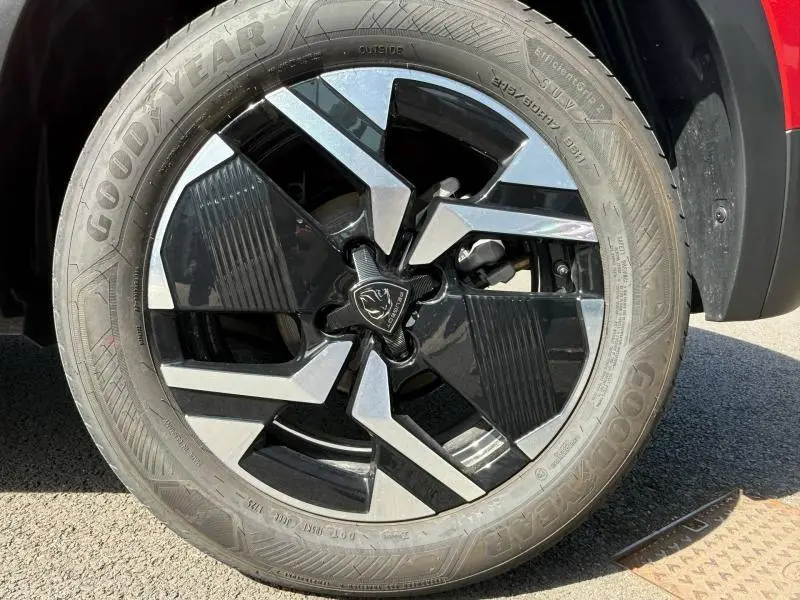 Gros plan sur la jante avant droite du Peugeot 2008 Rouge Elixir, avec un design moderne bicolore noir et argent.
