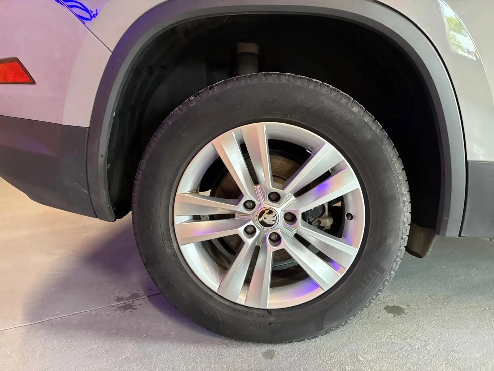 Gros plan sur la roue avant droite d'un Skoda Kodiaq gris clair, mettant en valeur la jante alliage et le logo central.