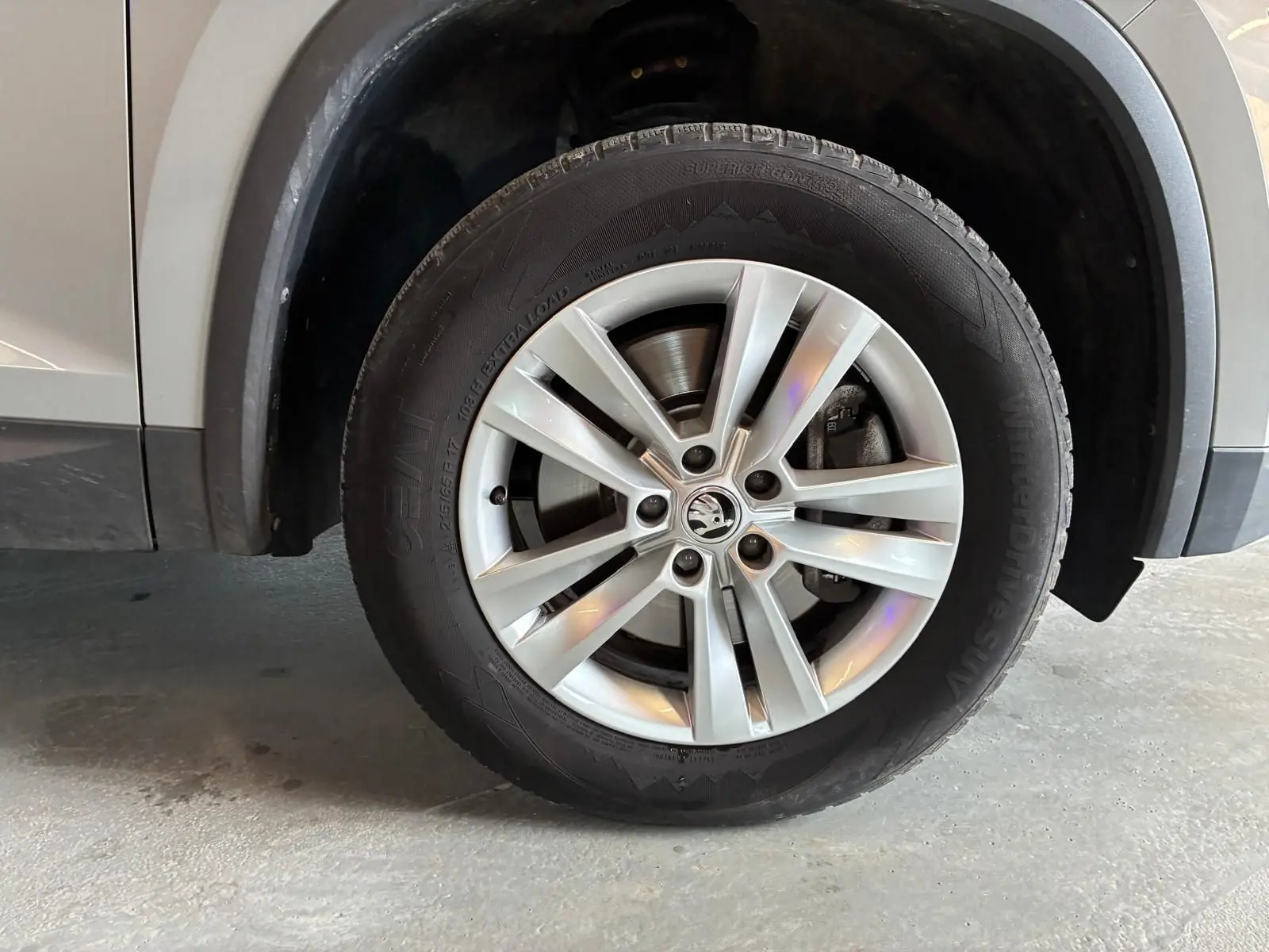 Gros plan sur la roue avant gauche d'un Skoda Kodiaq gris clair, mettant en valeur la jante alliage et le pneu hiver.