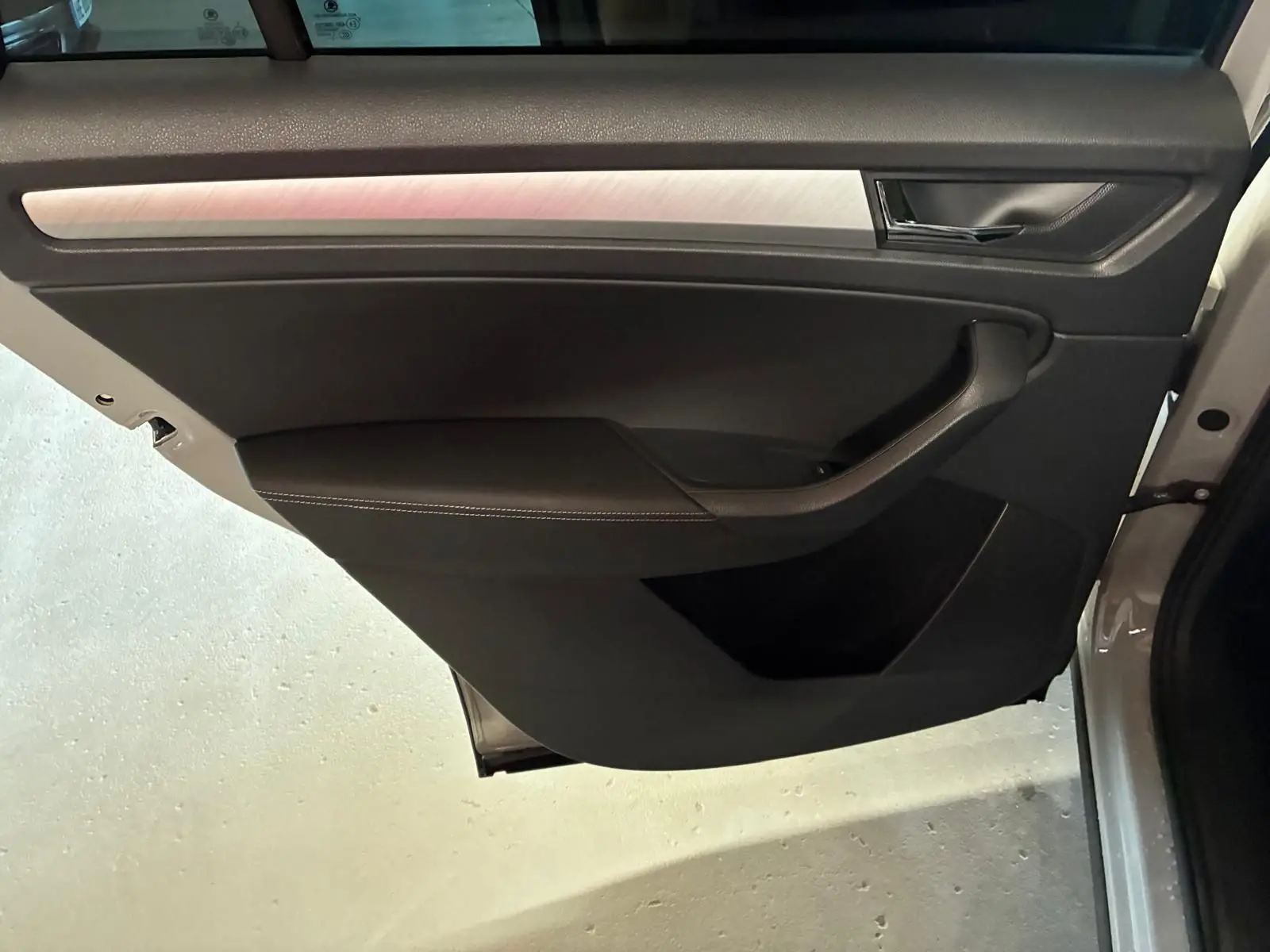 Vue rapprochée de la porte avant gauche gris clair d’un Skoda Kodiaq 2023 avec garniture noire et insert métal brossé.