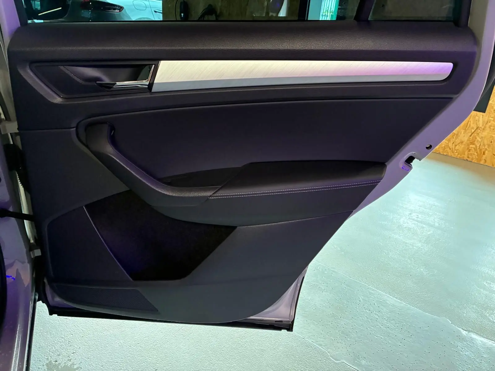 Vue intérieure de la porte arrière gauche du Skoda Kodiaq gris clair 2023, avec garniture noire et insert argenté.