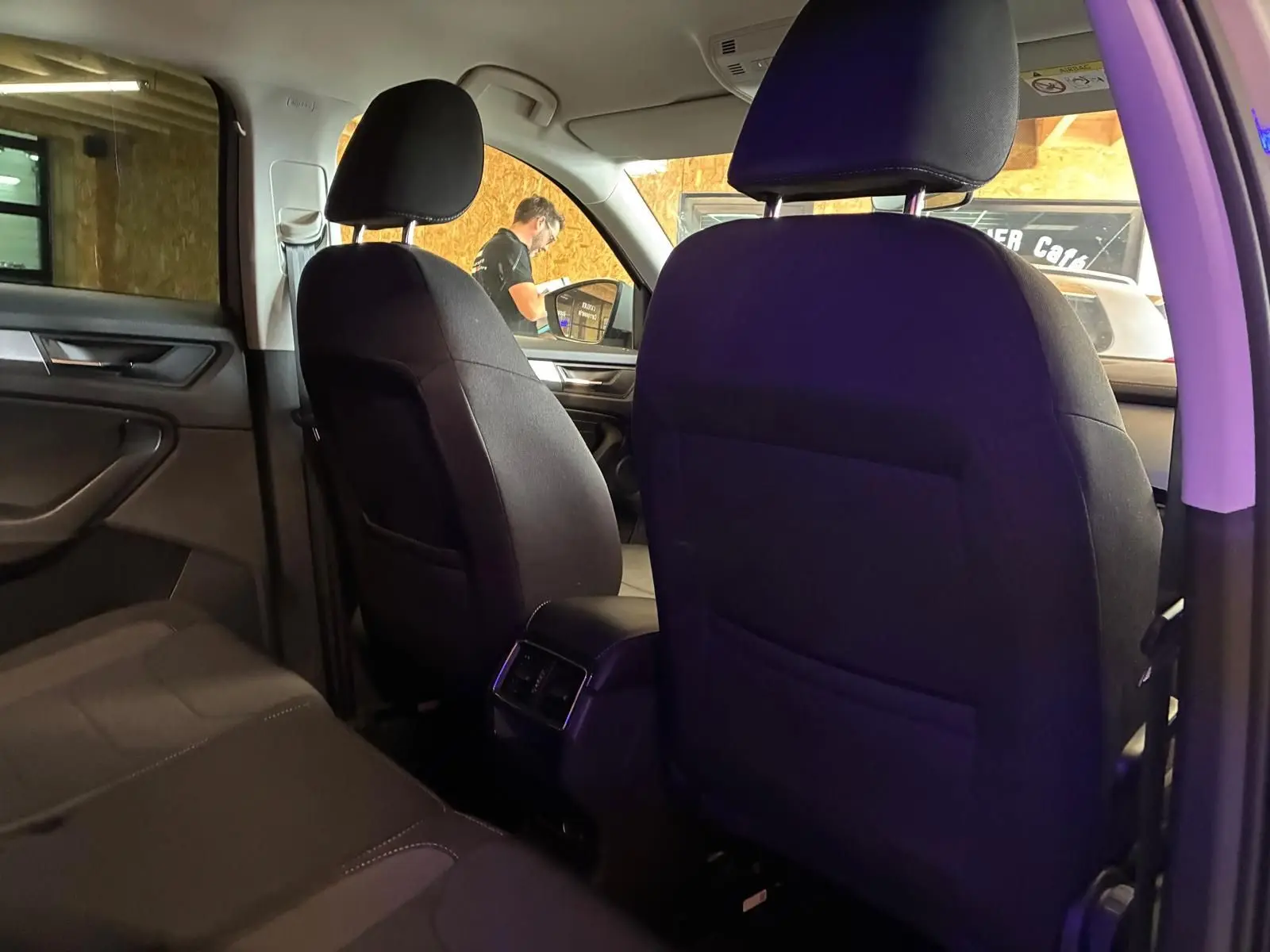 Vue intérieure arrière du Skoda Kodiaq 2023, sièges tissu noir et console centrale avec aérateurs arrière visibles.