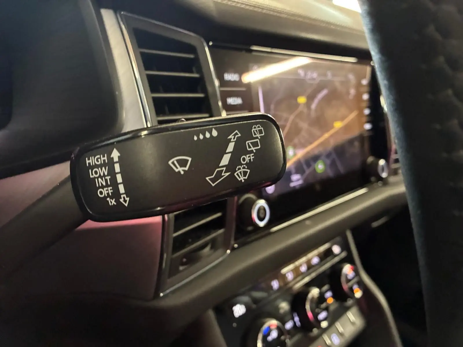 Gros plan sur la commande d’essuie-glace du Skoda Kodiaq gris clair 2023, avec tableau de bord et écran tactile en arrière-plan.