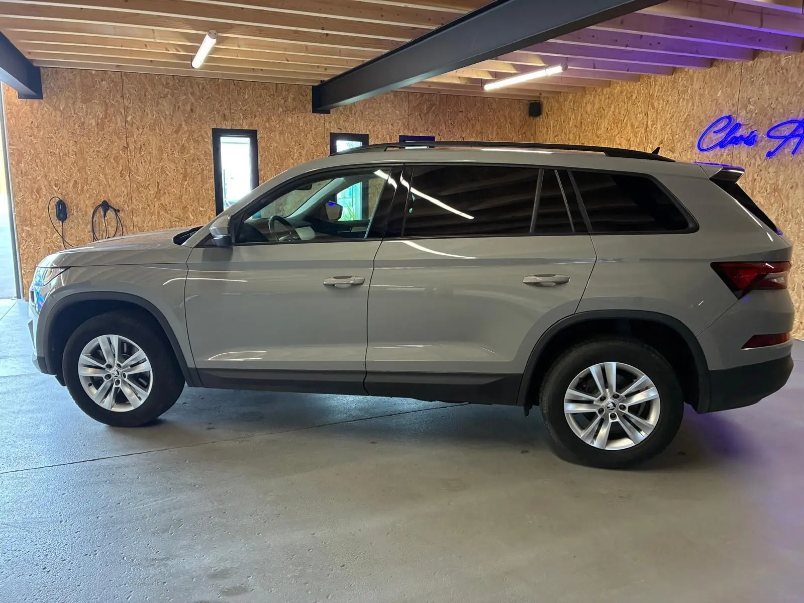 Profil droit d'un Skoda Kodiaq gris clair 2023, SUV 7 places avec jantes alliage et vitres teintées, en intérieur.