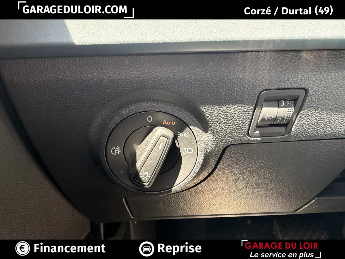 Gros plan sur le bouton de commande des phares et réglage hauteur sur tableau de bord noir d'une SEAT Arona 2025.