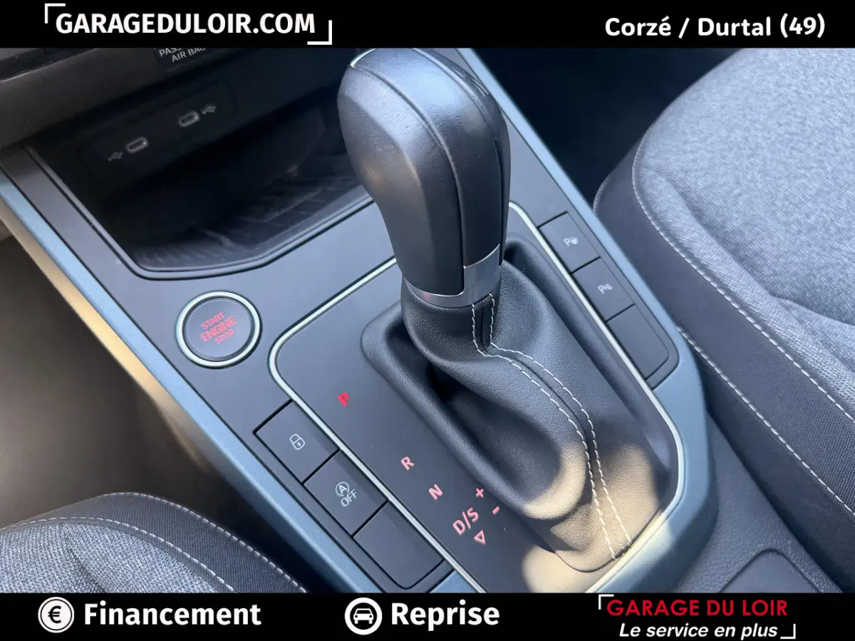 Gros plan sur la commande de boîte automatique noire avec coutures blanches et bouton start/stop rouge dans l'habitacle du SEAT Arona.