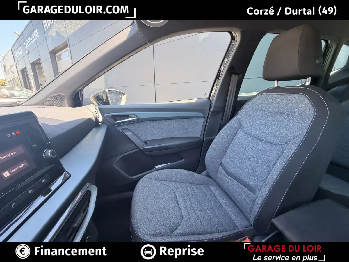 Vue intérieure côté passager avant du SEAT Arona 2025, siège gris tissu et tableau de bord avec écran tactile.