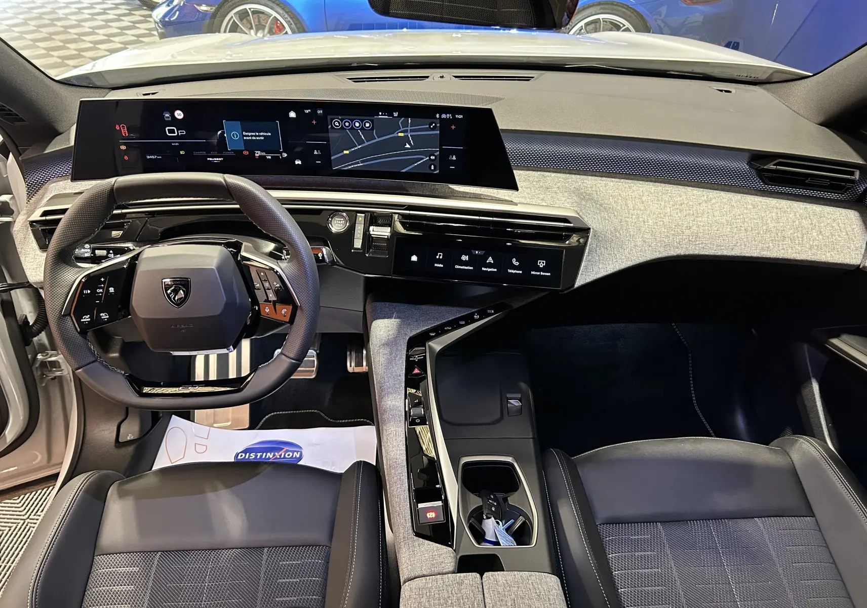 Vue intérieure du tableau de bord et volant du Peugeot 3008 Hybrid 2026 avec finition tissu et inserts gris clair.