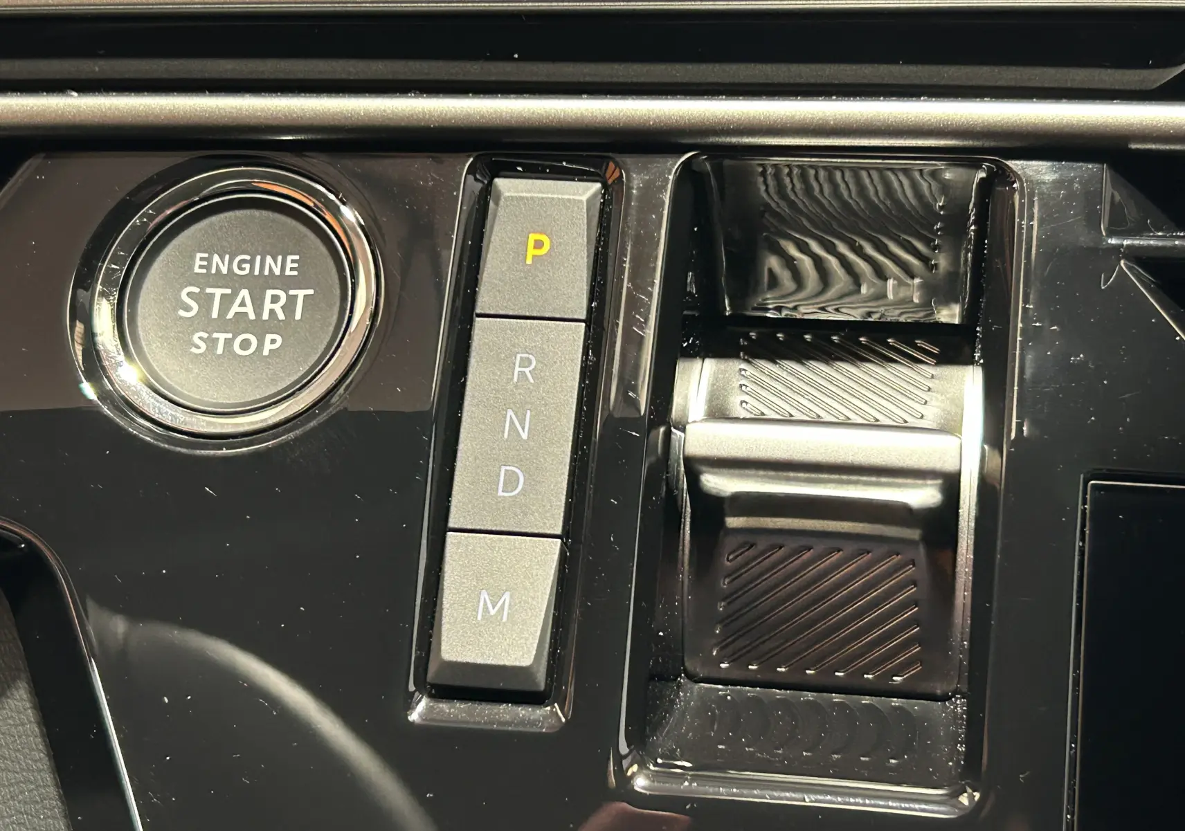 Gros plan sur la console centrale noire du Peugeot 3008 Hybrid avec bouton start/stop et sélecteur de vitesses électronique.
