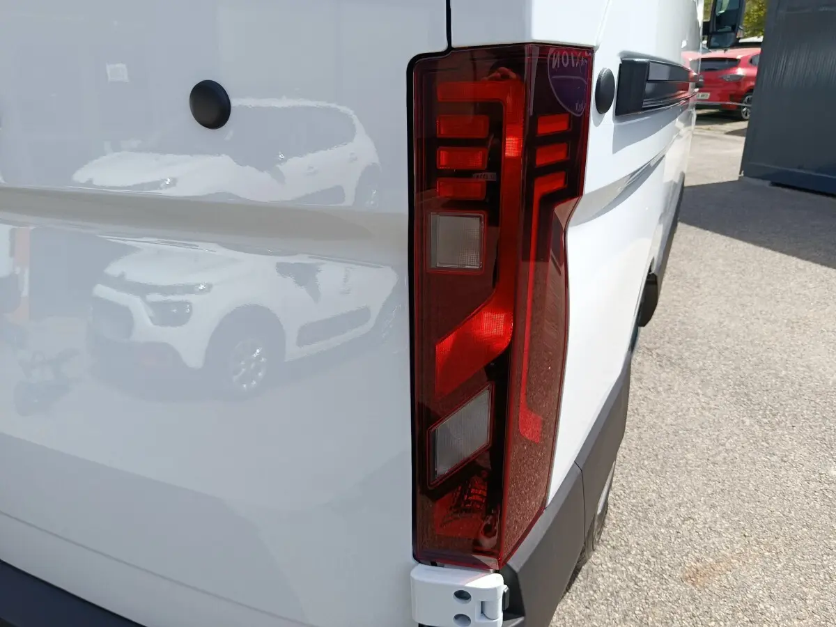 Gros plan sur le feu arrière droit du Renault Master blanc, mettant en valeur la surface rouge et les détails lumineux.