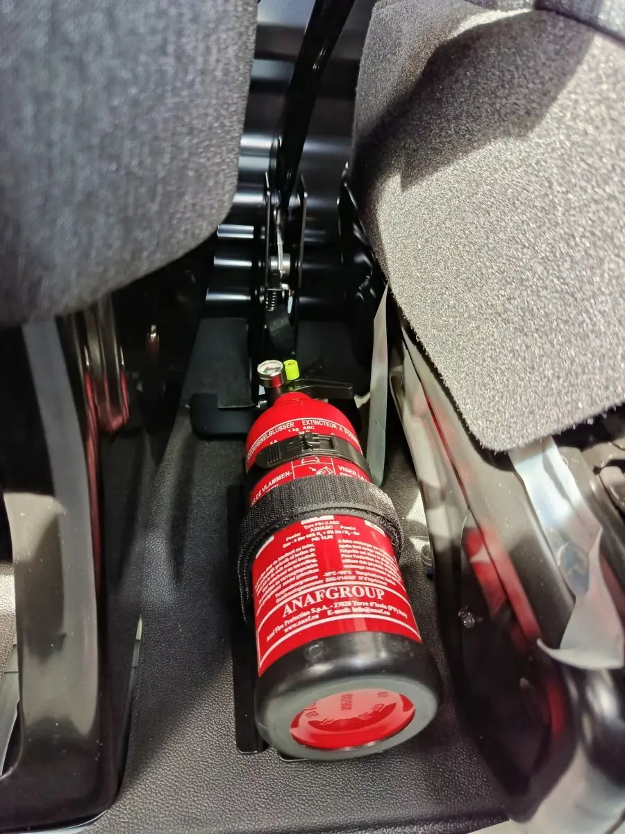 Gros plan intérieur sous siège montrant un extincteur rouge fixé dans un Renault Master blanc 2025.