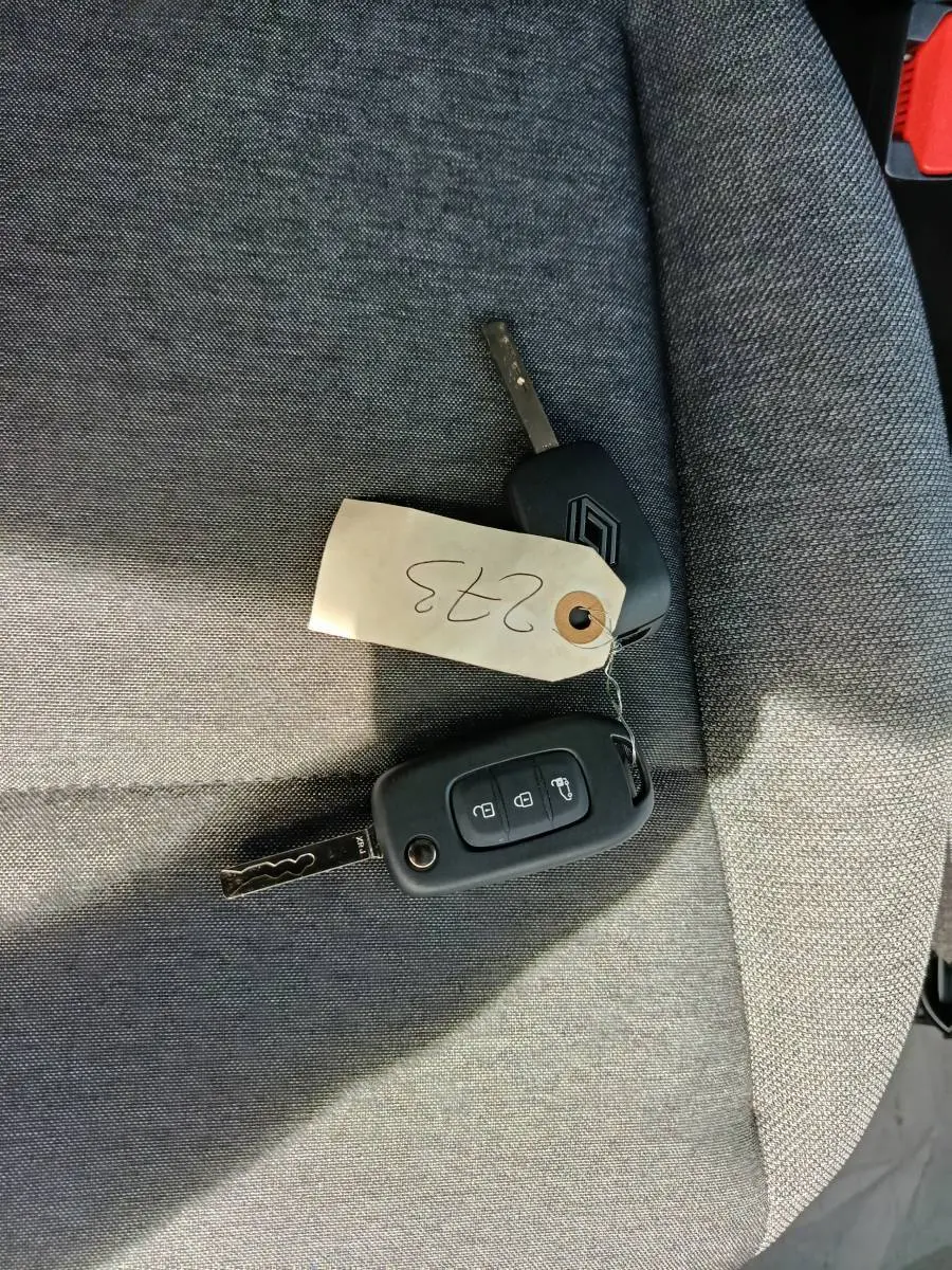 Gros plan sur deux clés Renault posées sur un siège tissu gris, avec une étiquette numérotée 0233.