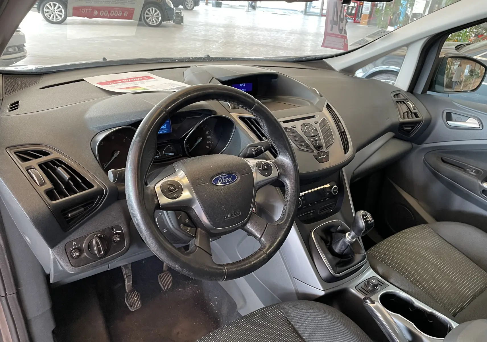 Intérieur de Ford C-MAX 2012 gris, vue côté conducteur sur le volant, tableau de bord et levier de vitesse manuel.