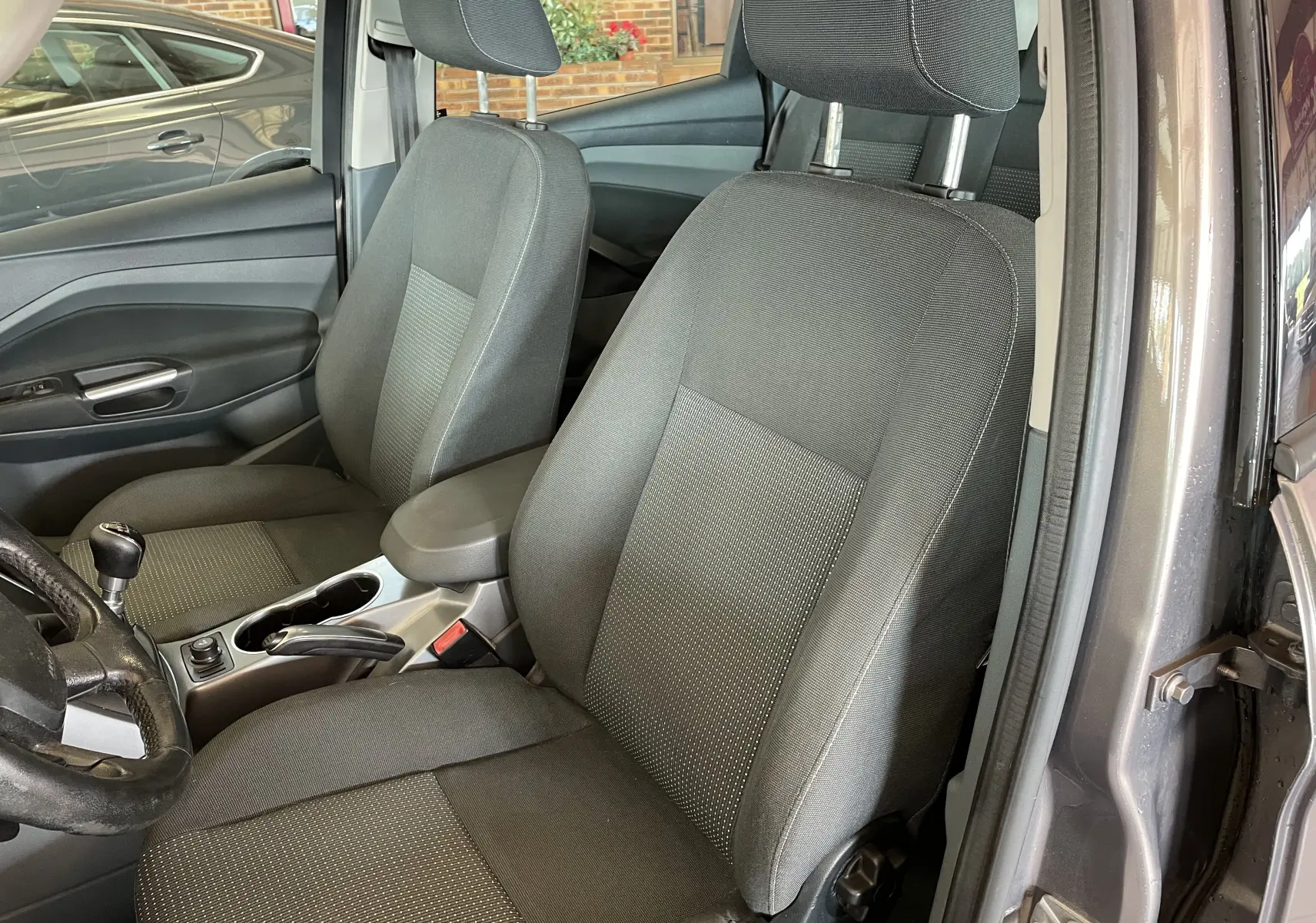 Intérieur avant de la Ford C-MAX gris 2012, vue côté conducteur montrant sièges en tissu noir et levier de vitesse manuel.
