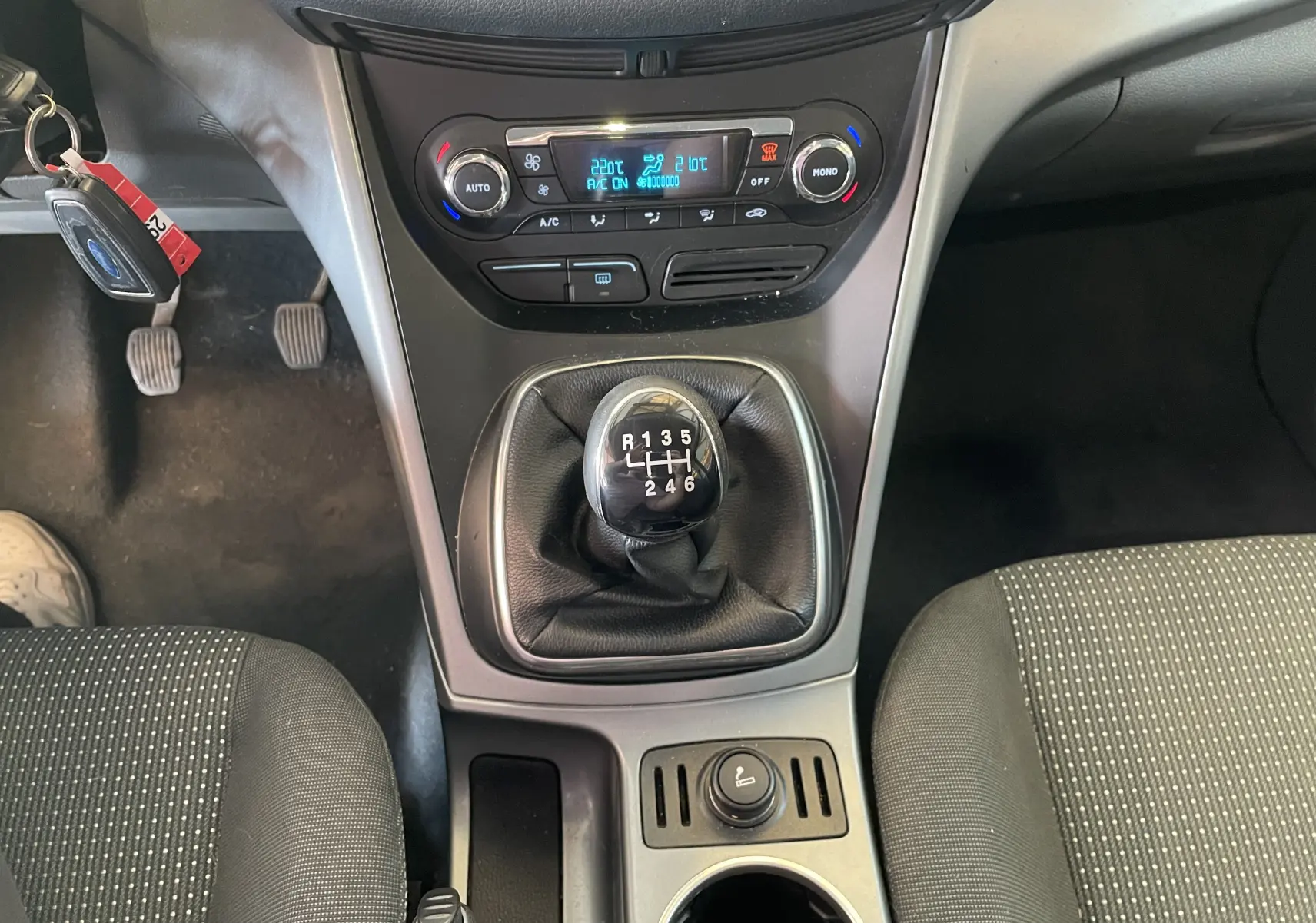 Vue plongeante sur la console centrale du Ford C-MAX gris 2012, mettant en valeur le levier de vitesse manuel et la climatisation digitale.