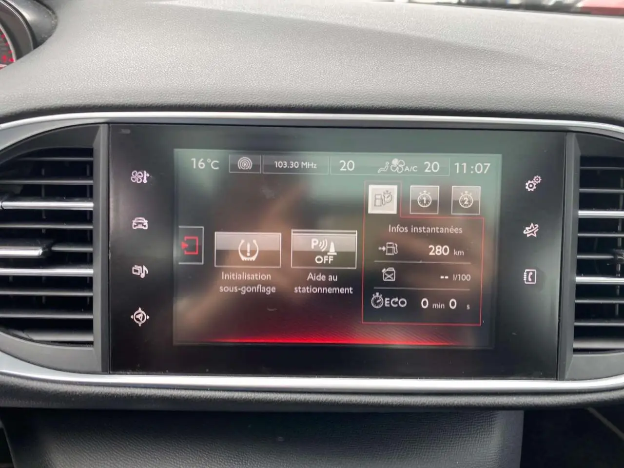 Écran tactile central du tableau de bord de la Peugeot 308 GTi 2016 affichant les aides à la conduite et la température intérieure.