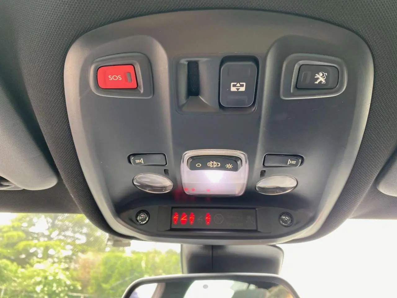 Vue du plafonnier intérieur avec bouton SOS rouge et commandes d'éclairage du Peugeot 308 GTi rouge 2016.